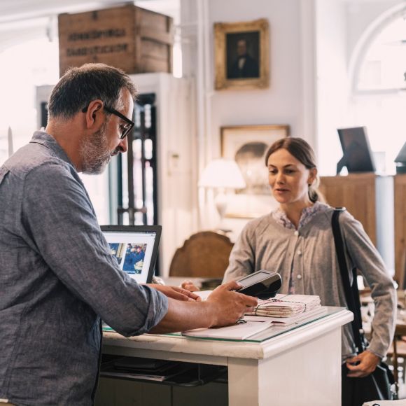 A merchant and a customer interact at a shop counter