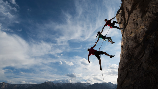 Three person repelling down cliff