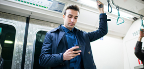 Um cliente do sexo masculino no metrô revisando suas mensagens personalizadas de uso de rede do provedor de serviços.