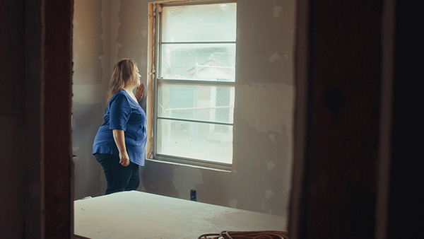 Hurricane victim looking out the window of her home that is being rebuilt