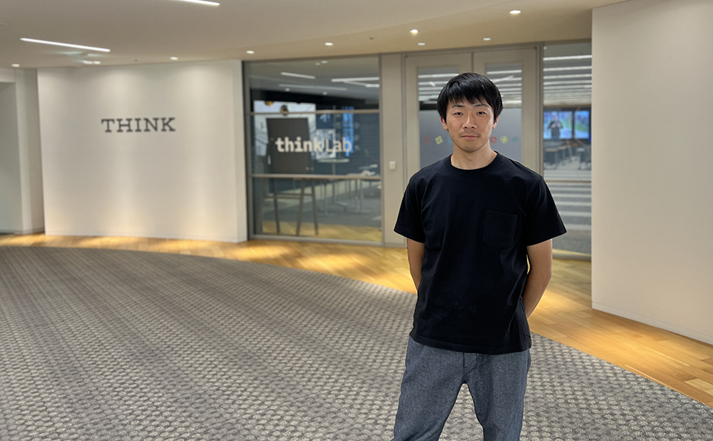 man standing in IBM office in Japan with THINK sign behind