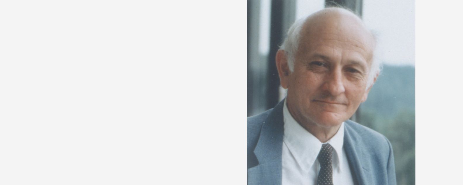 Close-up of John Cocke, smiling at the camera in a suit and tie