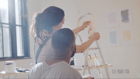 Pasangan yang sedang beristirahat dari melukis DIY, mendiskusikan contoh cat