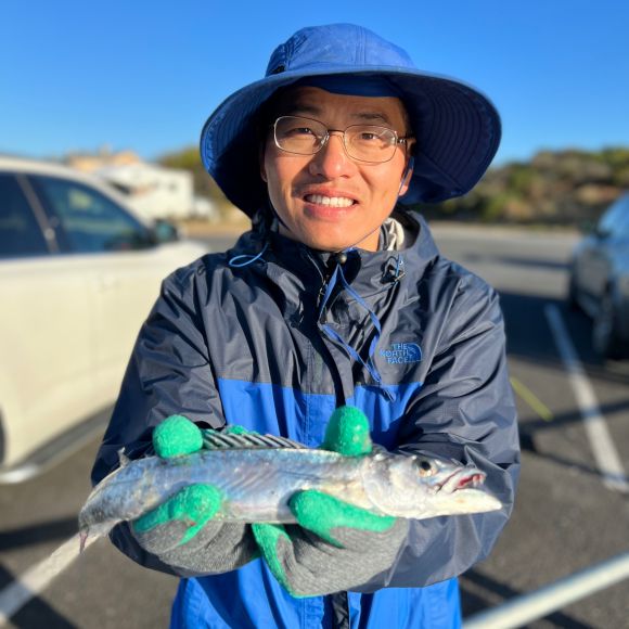 Employee posing outside holding a fish 