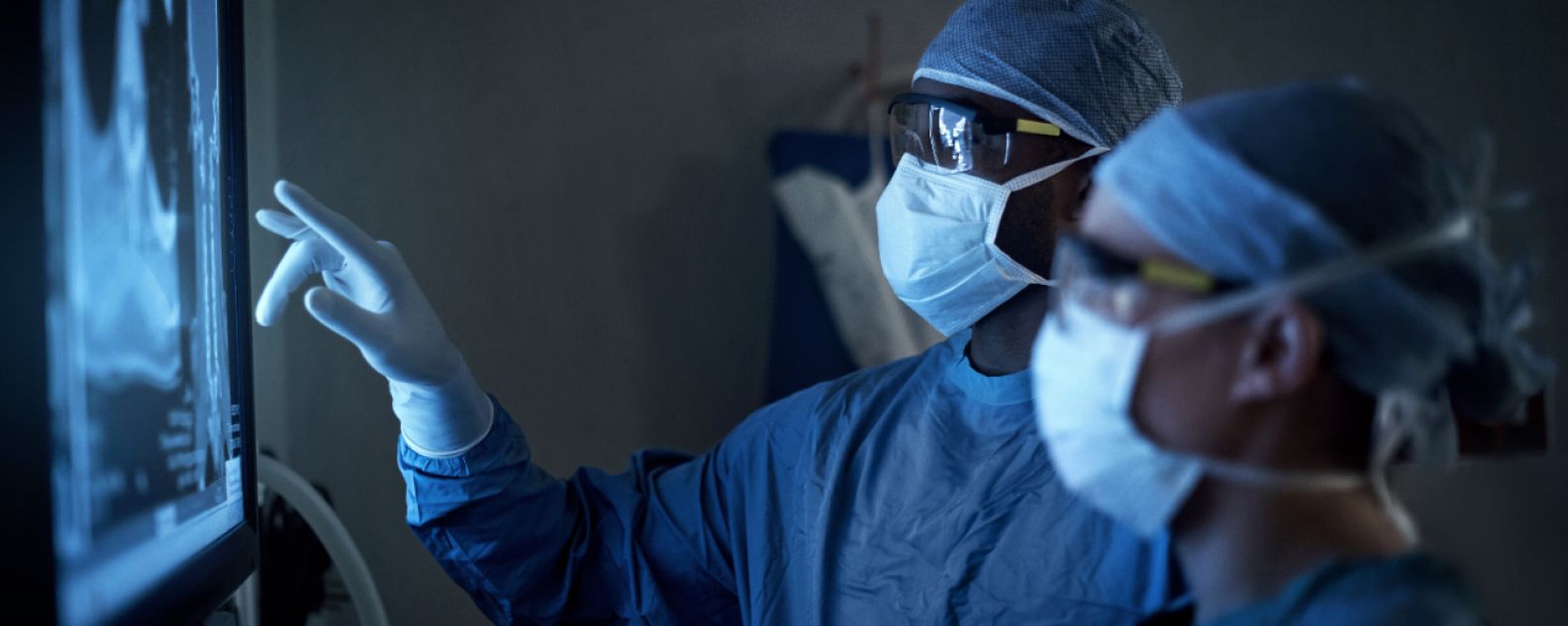 Foto de dois cirurgiões analisando imagens médicas de um paciente durante cirurgia