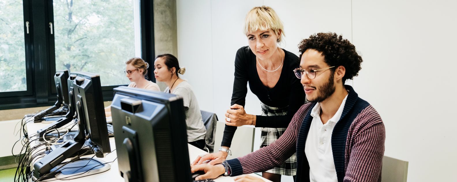 Manager helping employee on desktop computer in office