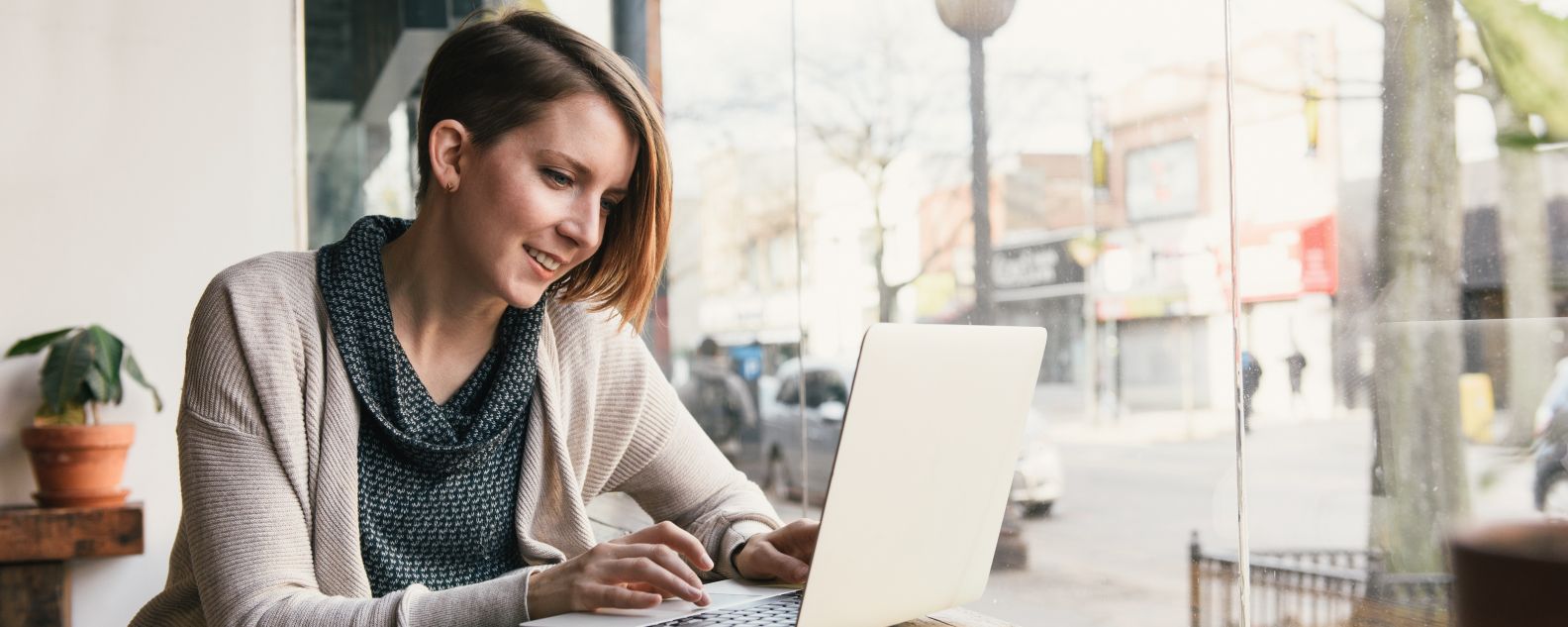 Person sitting in an office, smiling while working on a laptop computer