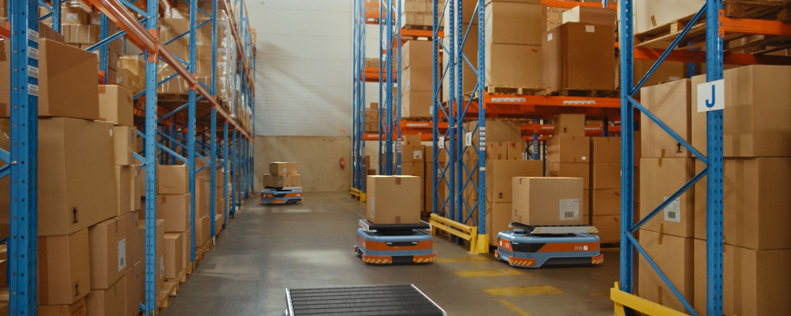 Robots de vehículos guiados automatizados (AGV, siglas en inglés de Automated Guided Vehicle) que transportan cajas de cartón en un almacén