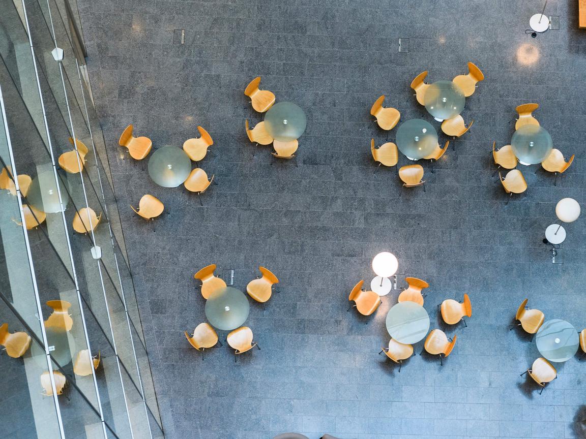 Top view on groups of glass tables with wooden chairs in industrial environment