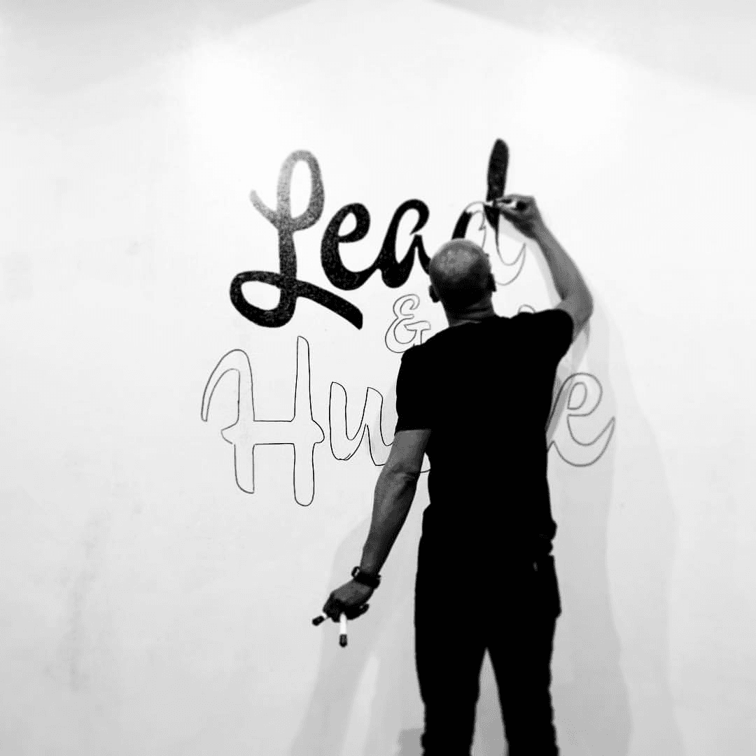 Oen sketching up Lead and Hustle on a big whiteboard—the logo from his design leadership bootcamp