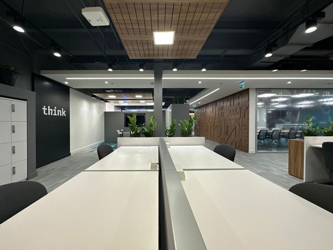 Think wordmark wall installation facing wood pattern wall across open area with individual workstations