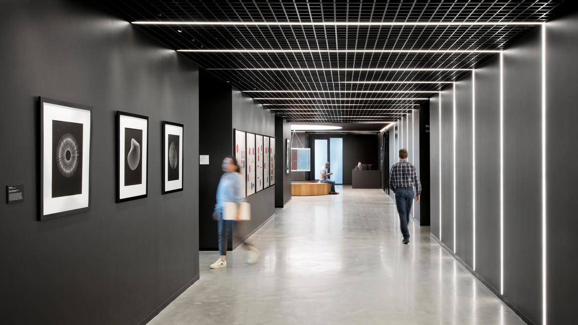 hallway with photos and posters opposite linear lighting panels