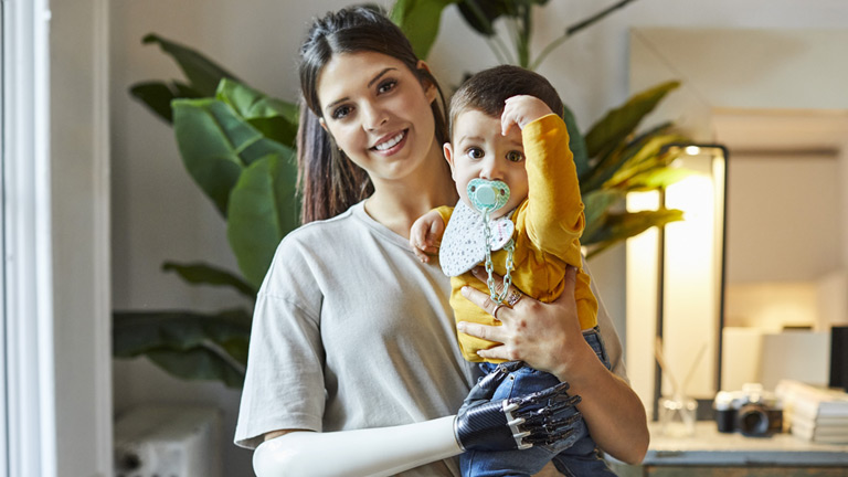 Woman with robotic arm and hand holding baby