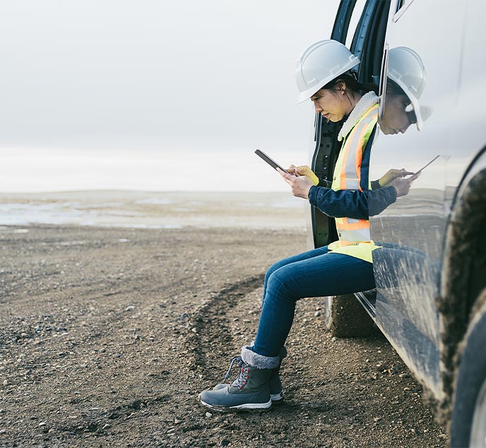 Field service technician sitting in service vehicle using tablet at work site