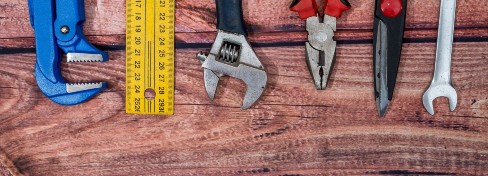 Wrenches, ruler, pliers lined up on a wooden table