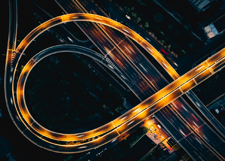 Yellow-orange lights with cars blurred in motion on highway and circular ramps at night