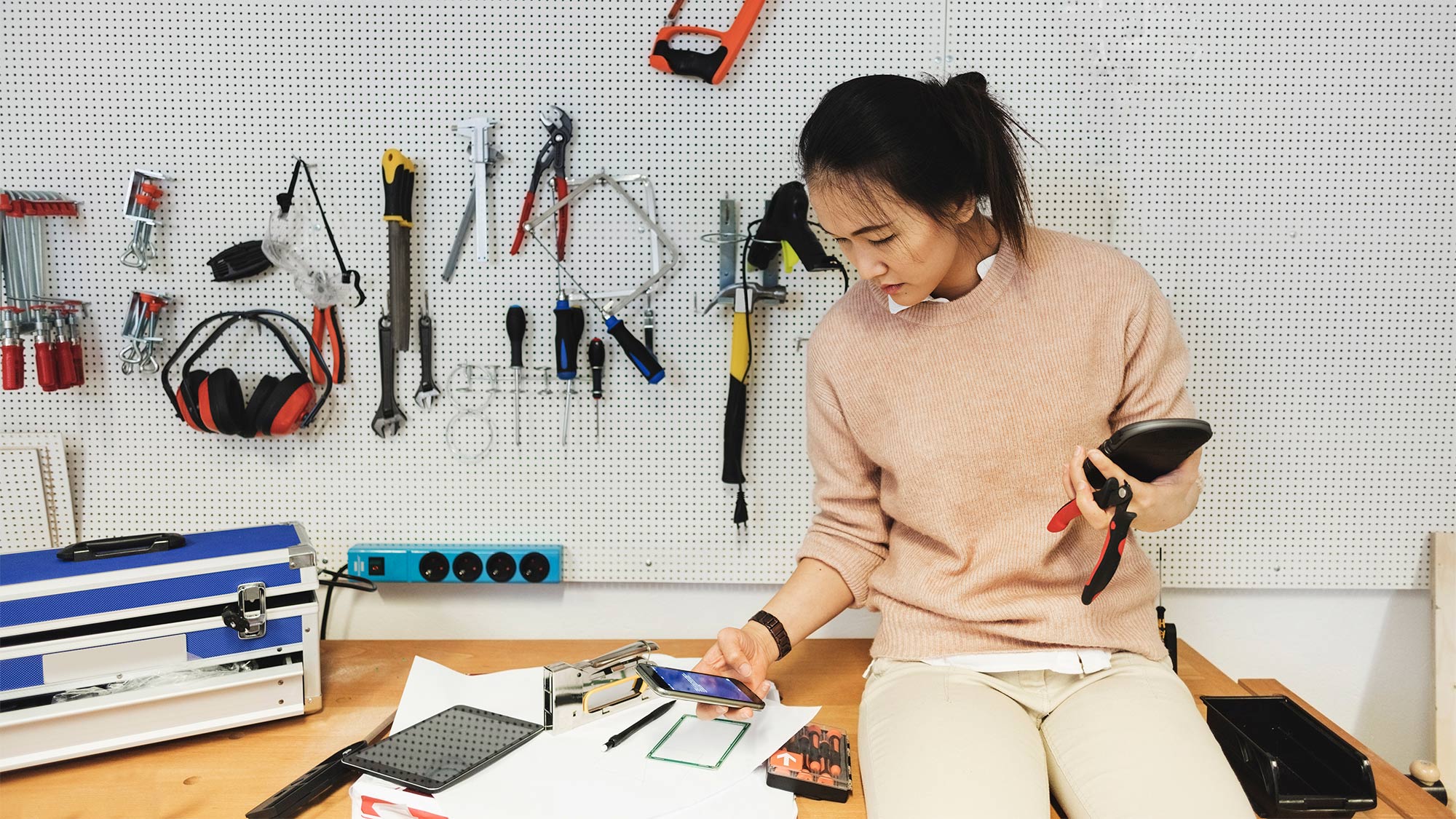 Eine Frau mit ihrem Smartphone arbeitet in ihrer Garage - ein Beispiel dafür, wie die MFA überall Sicherheit bietet.