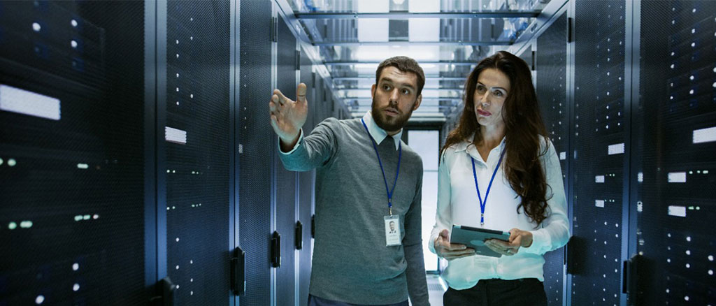 Male and female professionals in a server room.