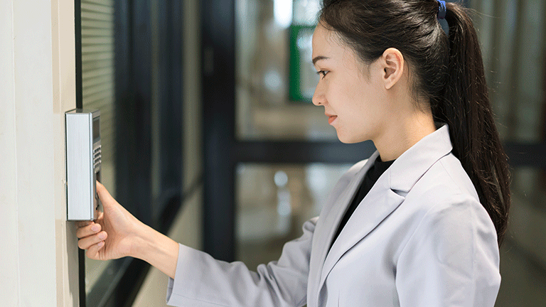 Professional woman using thumb print ID scanner in hallway